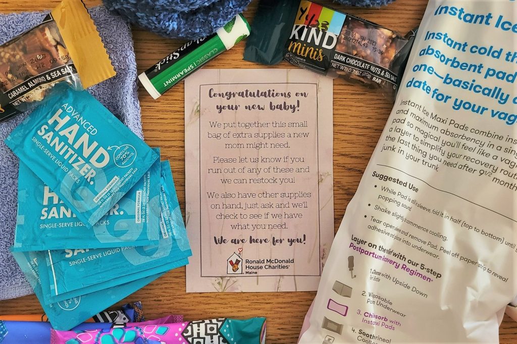 A collection of supplies including hand sanitizer, snacks, and a card congratulating new parents on their baby.