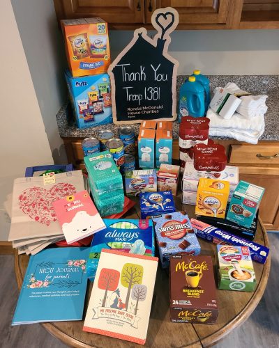 A table filled with donated items, a sign that says "Thank You Troop 138," and snacks for Ronald McDonald House Charities.