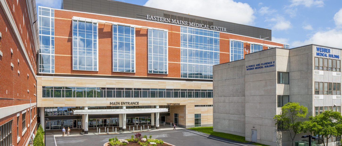 Modern medical center exterior featuring a main entrance and adjacent medical buildings. Bright, sunny day.