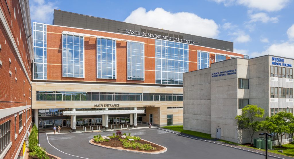Eastern Maine Medical Center's main entrance is shown, featuring modern architecture and landscaped pathways.