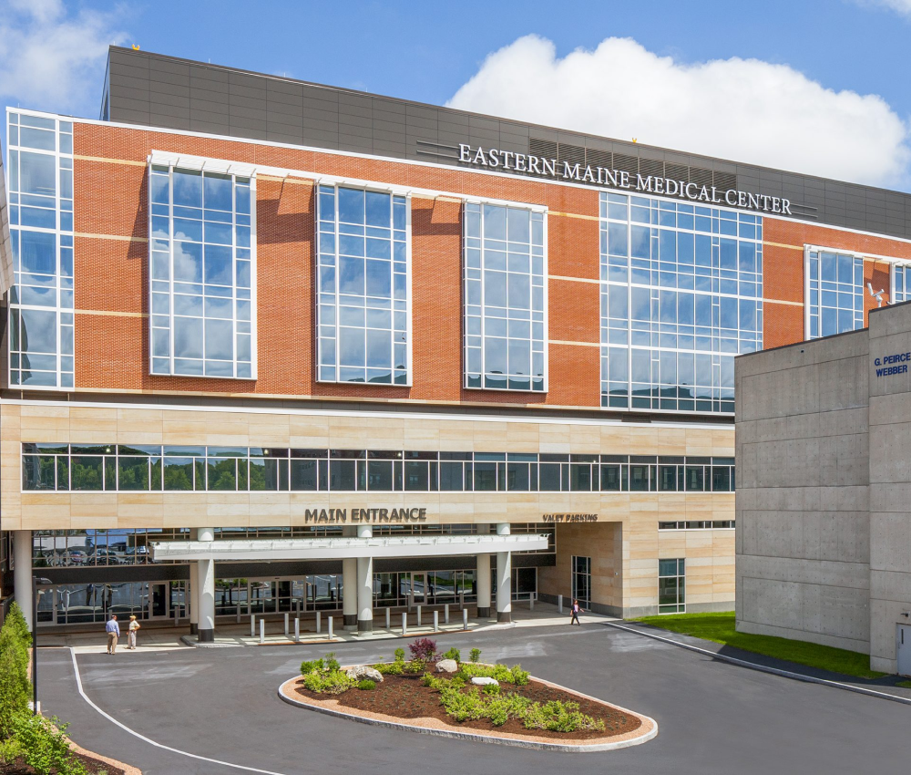 Modern hospital building with large windows and a welcoming entrance, surrounded by landscaped greenery.