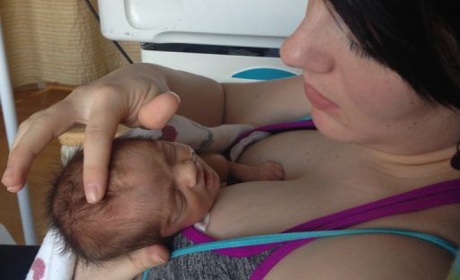 A mother cradles her newborn baby against her chest, both looking serene in a warm hospital setting.